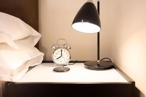 a bedside table with a clock and a lamp at Notting Hill - The One One One!!! -3- in London