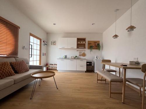 a living room with a couch and a table and a kitchen at Muji house Chiangmai 01 in Chiang Mai