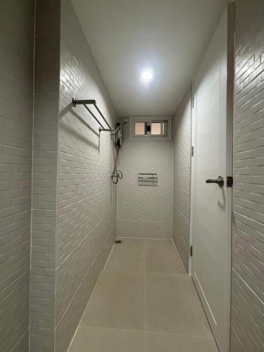 a walk in shower in a bathroom with white tiles at Muji house Chiangmai 01 in Chiang Mai