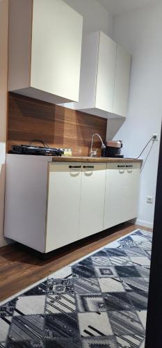 a kitchen with white cabinets and a rug at Prishtina Apartment in Prishtinë