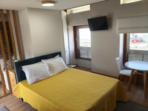 a bedroom with a bed with a yellow blanket and a table at Casa da Capela in Folgosa