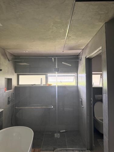 a bathroom with a toilet and a glass shower stall at 22 Mountain View in Herolds Bay