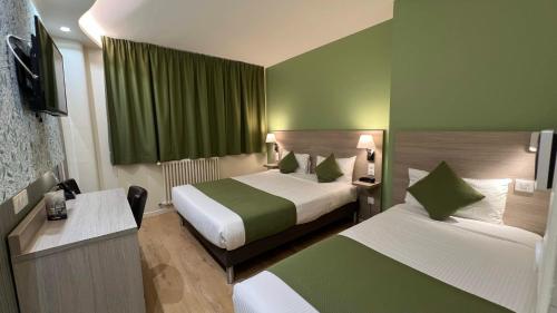 a hotel room with two beds with green walls at Contact Hôtel Le Continental in Vierzon