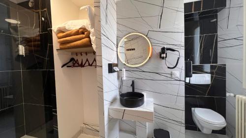 a bathroom with a toilet and a mirror on the wall at Contact Hôtel Le Continental in Vierzon