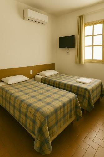 two beds sitting next to each other in a room at Alojamento Pousada Economica Canoas in Canoas
