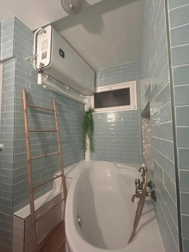 a bathroom with a tub and a blue tiled wall at Le Gouvernail in Le Tréport