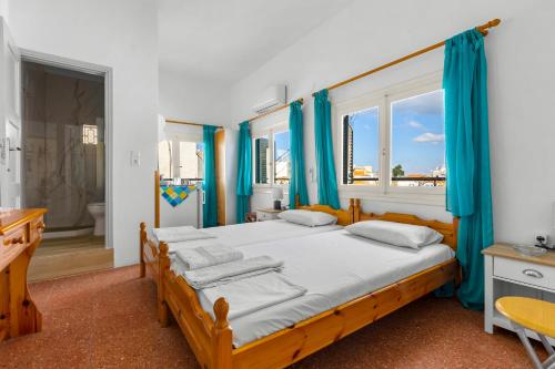 a bedroom with two beds and blue curtains at Κοχειλα Ματουλα Ενοικιαζόμενα Δωμάτια in Spetses
