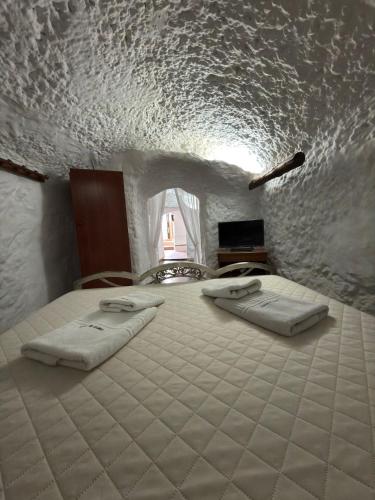 a bedroom with a bed with two towels on it at Casa Cueva Conde in Guadix