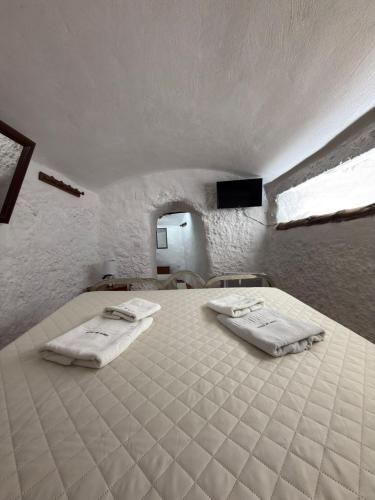a bedroom with a large bed with two white towels at Casa Cueva Conde in Guadix
