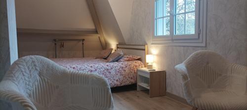 a bedroom with a bed with two chairs and a window at L'HIBISCUS de l'Audière in Malaunay