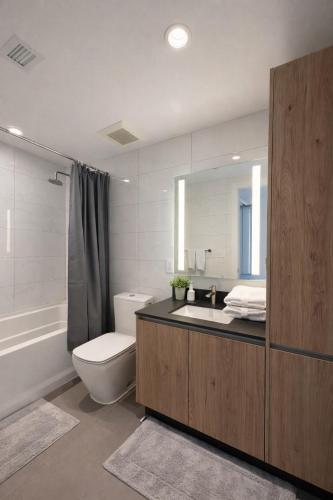 a bathroom with a sink and a toilet and a mirror at Prime Miami location - Modern Skyline Stay in Miami