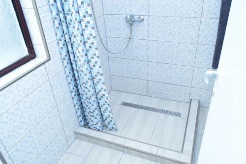 a bathroom with a shower with a blue shower curtain at Hotel Road Rooms in Voluntari