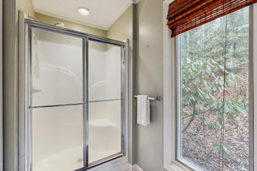 a bathroom with a glass shower door and a window at Sugar High in Sugar Mountain