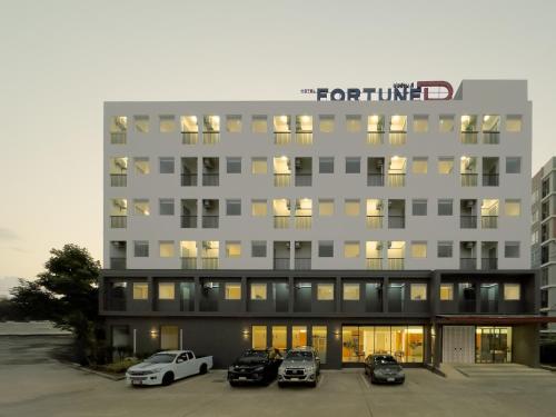 a tall building with cars parked in a parking lot at Fortune D Hotel Maesot in Mae Sot
