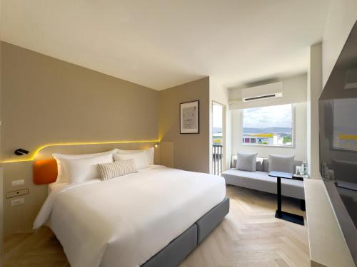 a bedroom with a large white bed and a desk at Fortune D Hotel Maesot in Mae Sot
