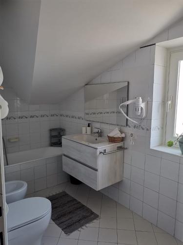 a white bathroom with a sink and a toilet at La casa di Ely in Sarno