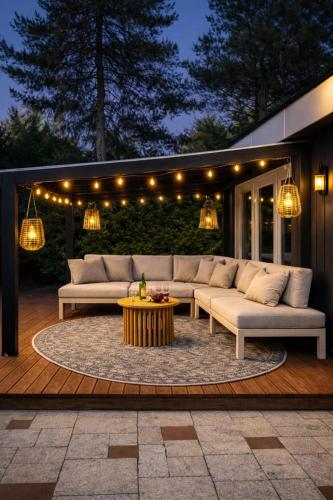 a patio with a couch and a table and lights at Natuurhuisje met omheinde tuin hond welkom stijlvol ingericht StayatSas Julia in Epe