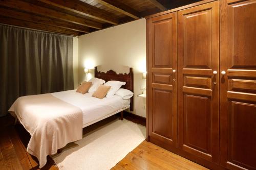 バケイラ・ベレットにあるVal de Ruda 12 by FeelFree Rentalsの白いベッドと木製キャビネット付きのベッドルーム1室が備わります。