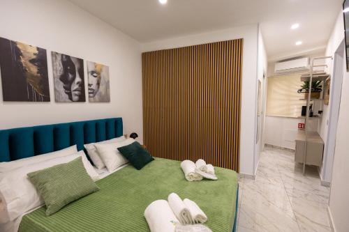 a bedroom with a green bed with towels on it at Kyma Apartment - Giardini Naxos in Giardini Naxos