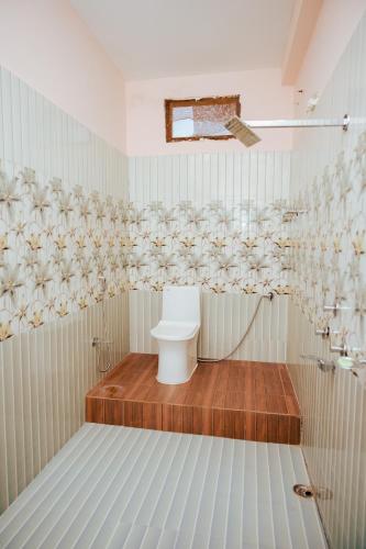 a white bathroom with a toilet and a shower at Hotel Saraswati in Nautanwa