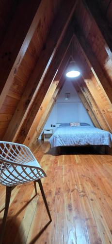 a room with a bed and a chair in a attic at Cabaña Alpina 2 in Coñaripe