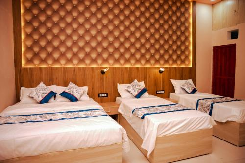 a bedroom with two beds with white sheets and blue pillows at Hotel Saraswati in Nautanwa