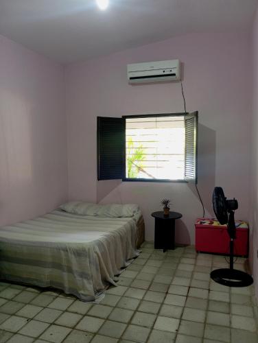 a bedroom with a bed and a window and a fan at Casa com piscina em Aldeia in Camaragibe