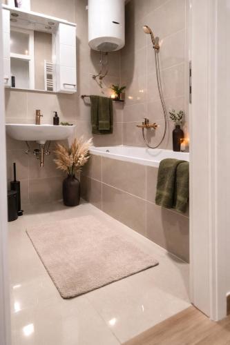 a bathroom with a tub and a sink and a shower at Avenoir Suite in Banja Luka