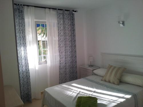 1 dormitorio con 1 cama y una ventana con cortinas en Frontbeach apartment in los Boliches, en Fuengirola