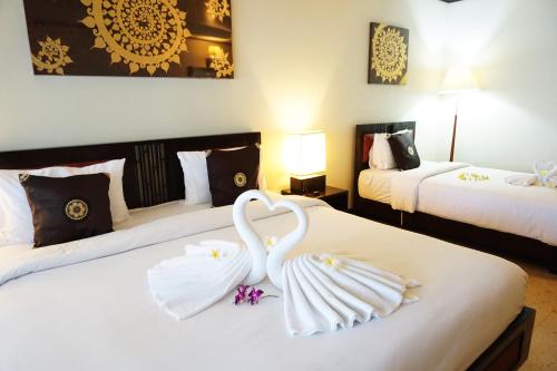 two swans sitting on a bed in a hotel room at Lamai Inn 99 Bungalows in Lamai