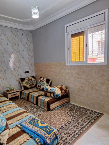 a bedroom with two beds and a couch and a window at Nawal's guest house in Tadouart