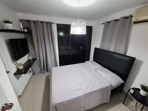 a bedroom with a bed with white sheets and a chandelier at Hermoso Loft in Santo Domingo