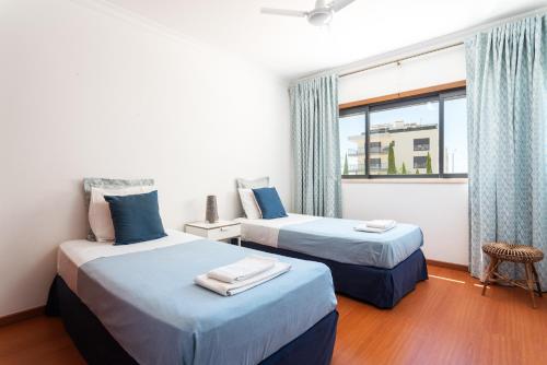 two beds in a room with a window at Santa Maria Apartamentos in Tavira