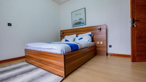 a bedroom with a bed with a wooden headboard at K&K Luxurious Landing in Limbe