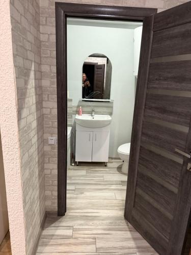 a bathroom with a sink and a person in a mirror at Апартамент студия in Khmelnytskyi