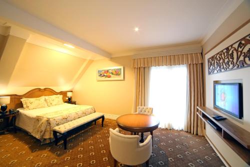 a hotel room with a bed and a television at Pousada Italia Eleganza in Campos do Jordão