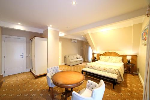 a hotel room with a bed and a table and chairs at Pousada Italia Eleganza in Campos do Jordão