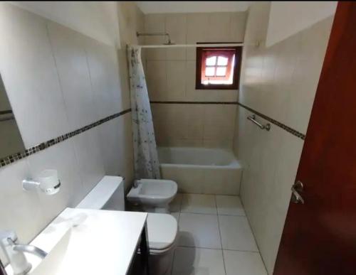 a bathroom with a toilet and a sink and a tub at Fede Tridente in Pinamar