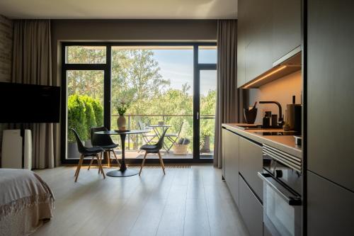 a kitchen with a table and chairs and a large window at SkyGarden Studio - Private Terrace and View in Quiet Jūrmala in Jūrmala