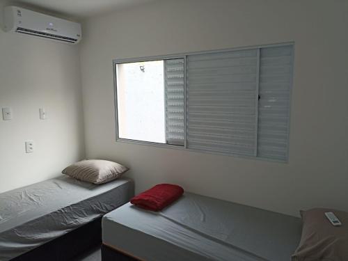a bedroom with two beds and a window with blinds at Itu Loft Pousada Girassol in Itu
