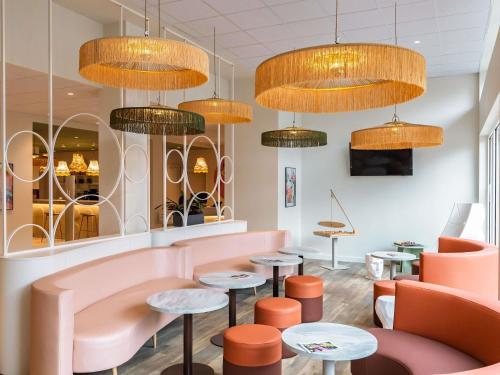 a restaurant with pink chairs and tables and chandeliers at ibis Styles Metz Centre in Metz