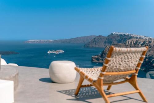 a chair sitting on a ledge with a view of the ocean at Nelya Suites in Megalochori