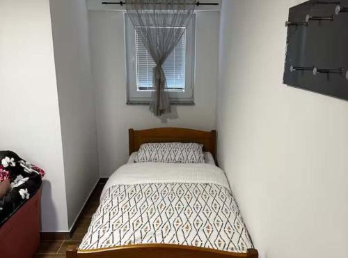 a small bedroom with a bed and a window at Sošice Garden Apartments in Sošice