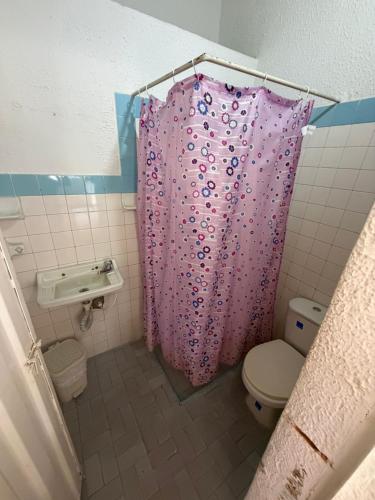 a bathroom with a pink shower curtain and a toilet at Brisas de melgar in Melgar