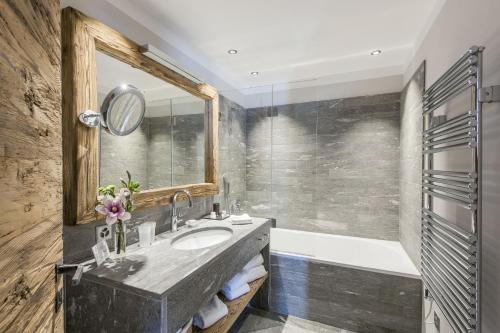 a bathroom with a sink and a tub and a mirror at Hotelino Petit Chalet in Celerina