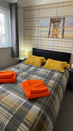 a bedroom with a bed with orange towels on it at The Three bs in Scratby