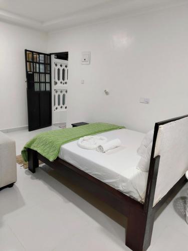 a bedroom with a bed with a green blanket at Diani Beach Studio with Pool, Beach Access in Diani Beach
