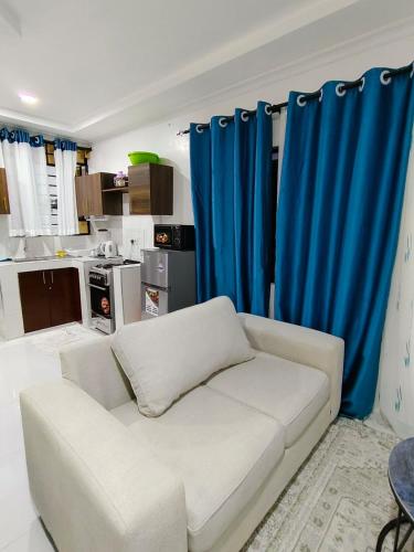a white couch in a living room with blue curtains at Diani Beach Studio with Pool, Beach Access in Diani Beach