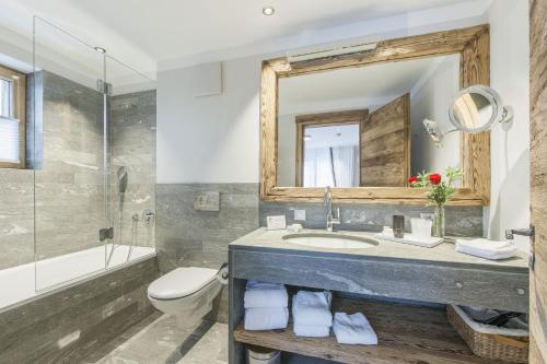 a bathroom with a sink and a toilet and a mirror at Hotelino Petit Chalet in Celerina