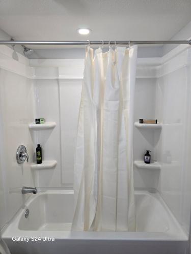 a white bath tub with a shower curtain in a bathroom at Omos Home in Saskatoon